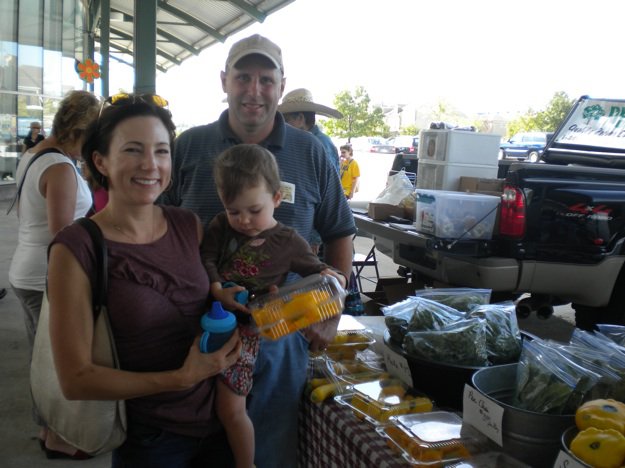 Leah Tonkin, her daughter Addie, and Tim Smith of Gracious Gardens get excited about squash blossoms at the Memphis Farmers Market.