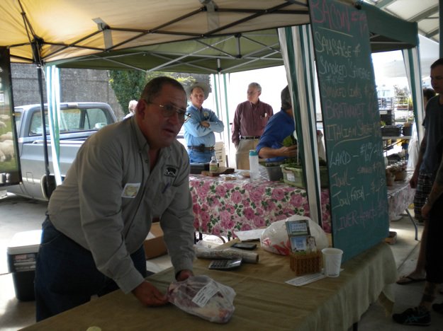 Mark Newman explains how to prepare a pork roast to a customer at the downtown market.

