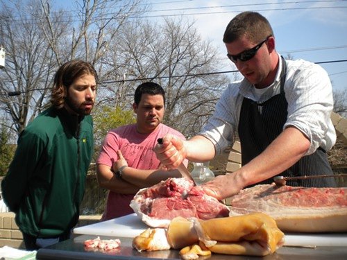 Andy Ticer and Michael Hudman watch David Newman demonstrate how to butcher a hog in the backyard of Andrew Michael Italian Kitchen.