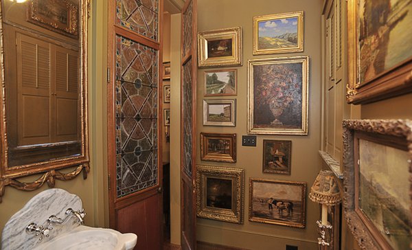 The powder room is a mini-museum with its floor-to-ceiling artworks, stained glass, and marble sink.