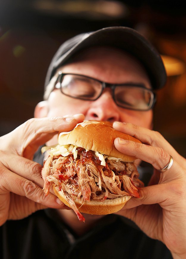 Biting into a classic pulled pork barbecue sandwich.