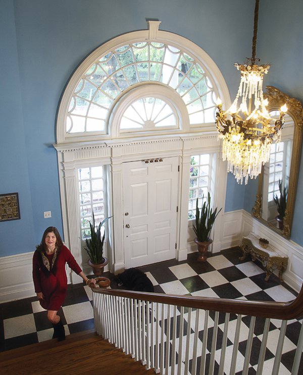 Martha McKay stands at the foot of the sweeping staircase in the Snowden House entry hall. This grand space didn't exist in the original house her grandfather built; it's one of the most impressive features of the 1949 renovation. The crystal chandel...