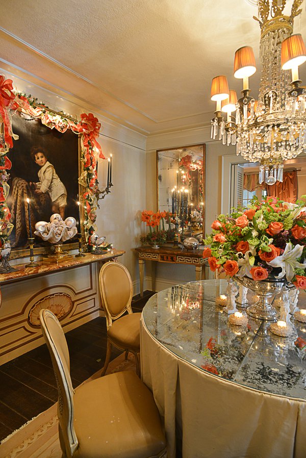 Candles, a crystal chandelier, and mirrored surfaces bathe the gorgeous dining room in a coral glow.