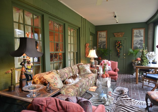 The Christmas-colored sunroom at the Moore home is an eclectic mix of architectural fragments, antique wallpaper panels, and a chintz-covered couch — all boldly anchored by a zebra rug.