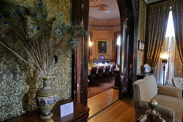 Looking from the small parlor/sitting room through a grand arch into the dining room with a vase of peacock feathers (an art nouveau flourish) in the foreground.