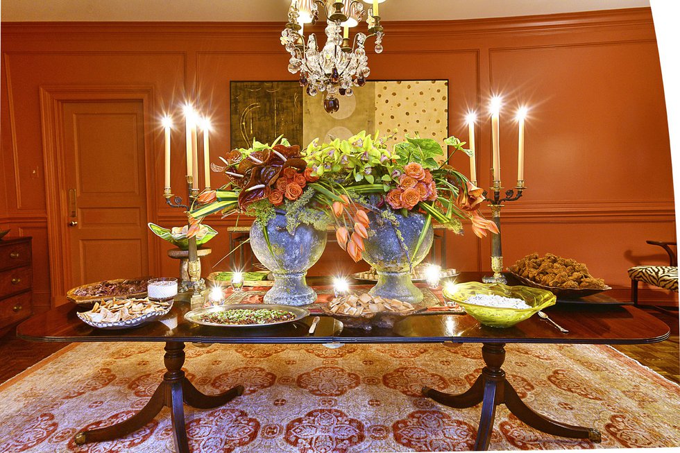 In Russell’s dining room two oversize rustic urns brimming with coral-hued flowers make a stunning centerpiece that complements the warm tones of the walls and accentuates the colors in the oriental rug. 
