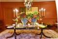 In Russell’s dining room two oversize rustic urns brimming with coral-hued flowers make a stunning centerpiece that complements the warm tones of the walls and accentuates the colors in the oriental rug. 