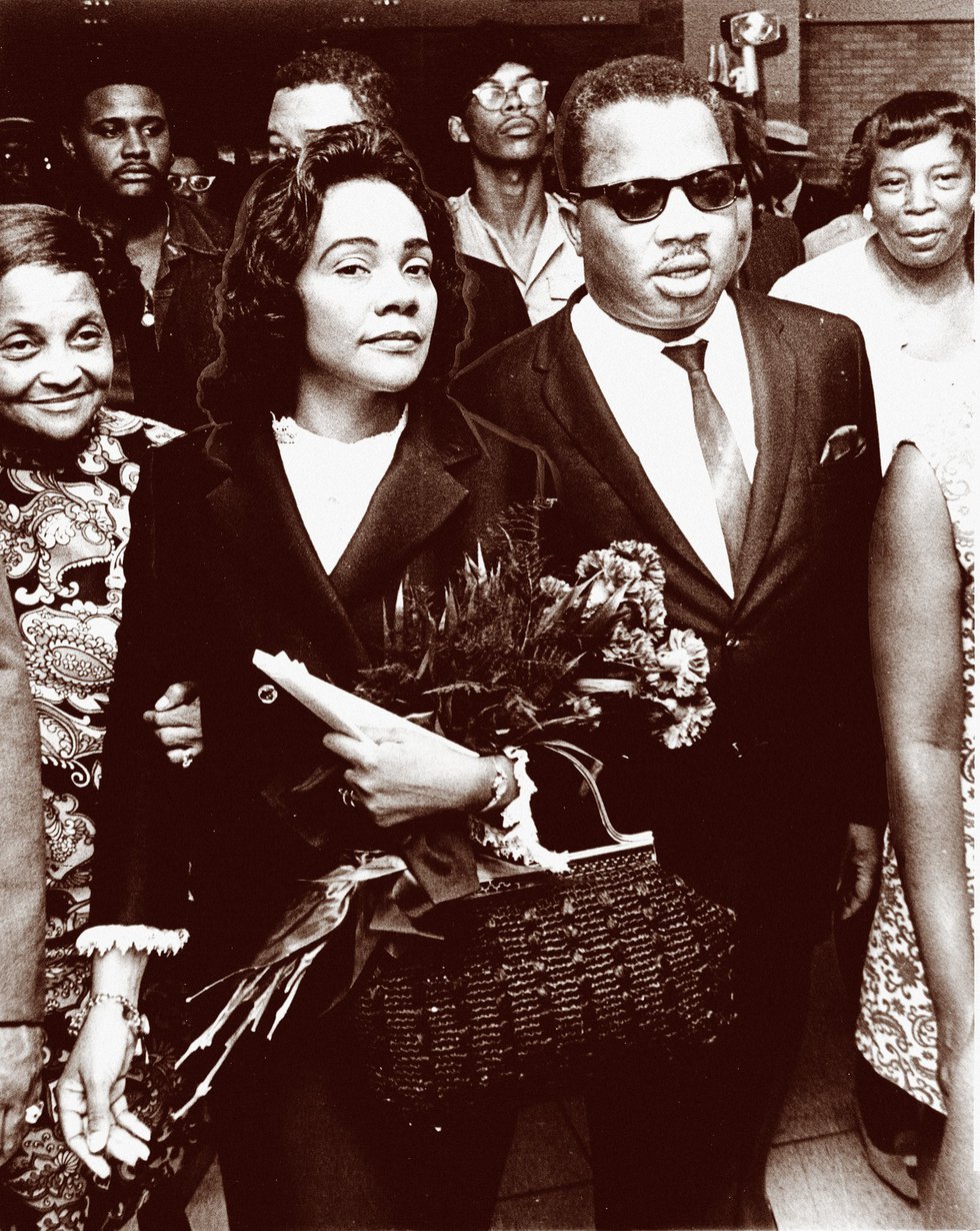 Carrying a bouquet of flowers given to her by mourners and supporters of her husband’s cause, Coretta Scott King is accompanied by A.D. King, the younger brother of Dr. Martin Luther King.
