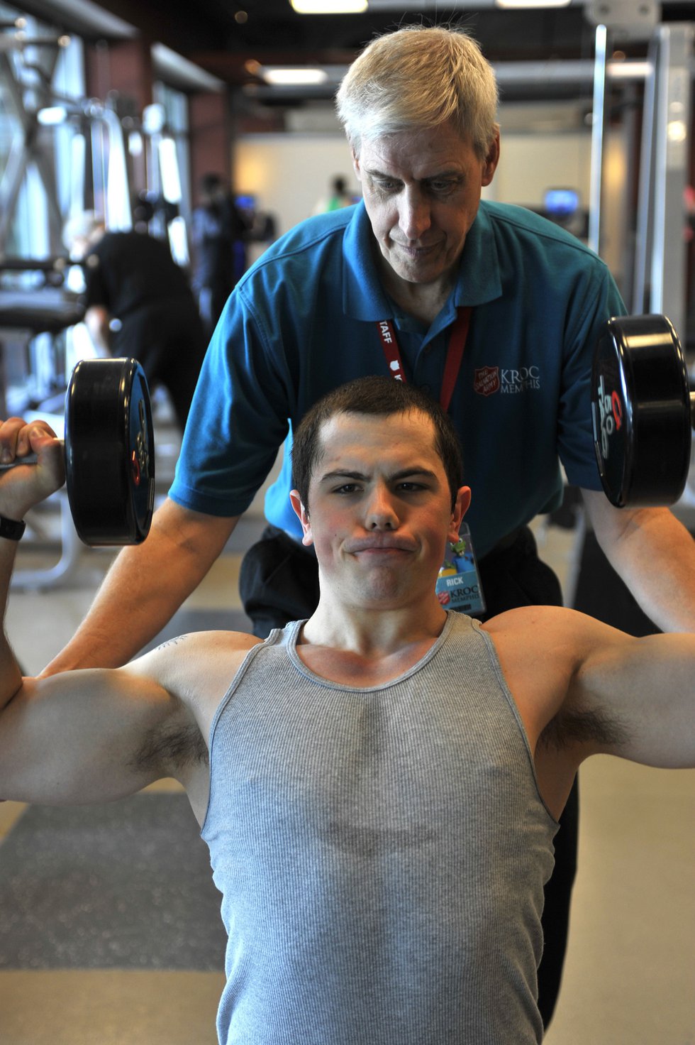 Program director Rick Ellis works with Neil Allen as he performs a dumbbell shoulder press in the fitness center, with its free weights, personal trainers, boot camp, treadmills, and more.