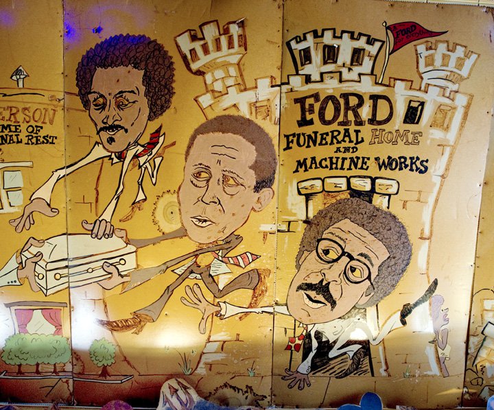 Dating from the 1980s, cartoonist Brad McMillan’s famous murals on the walls of the P&amp;H Cafe in Midtown include a Ford family section featuring brothers (left to right) James, Harold Sr., and John. | photograph by Brandon Dill
