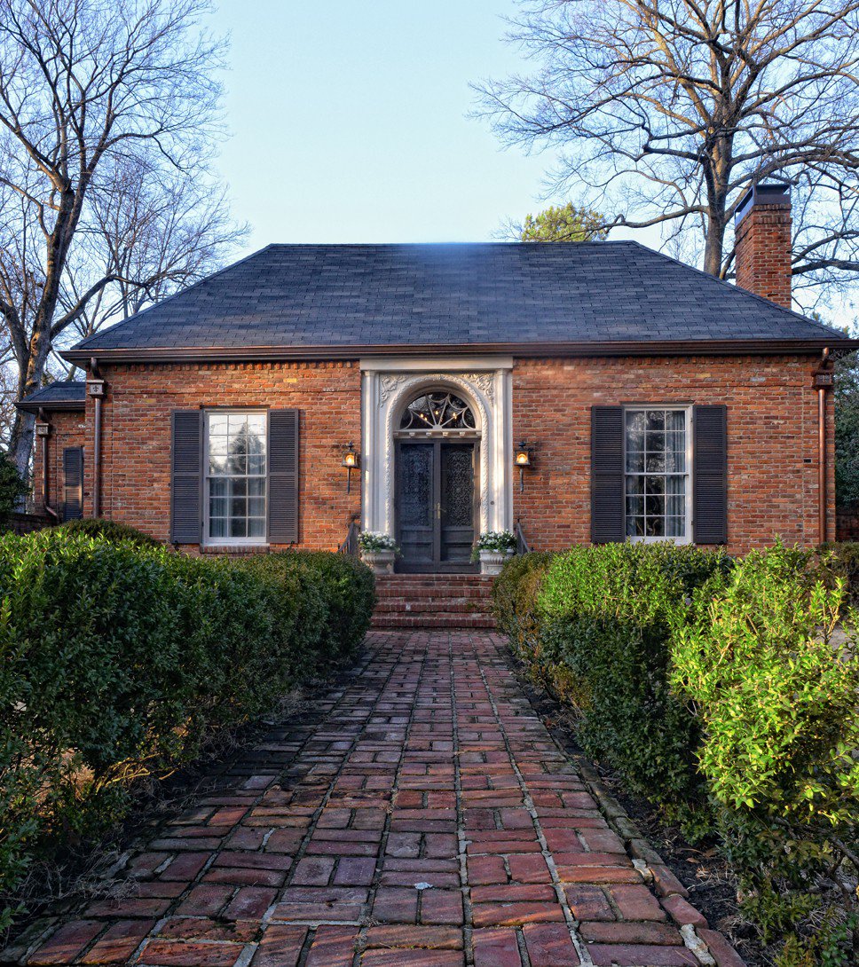 An old brick walkway lined with boxwoods leads visitors up to this historic jewel box of a house. 
