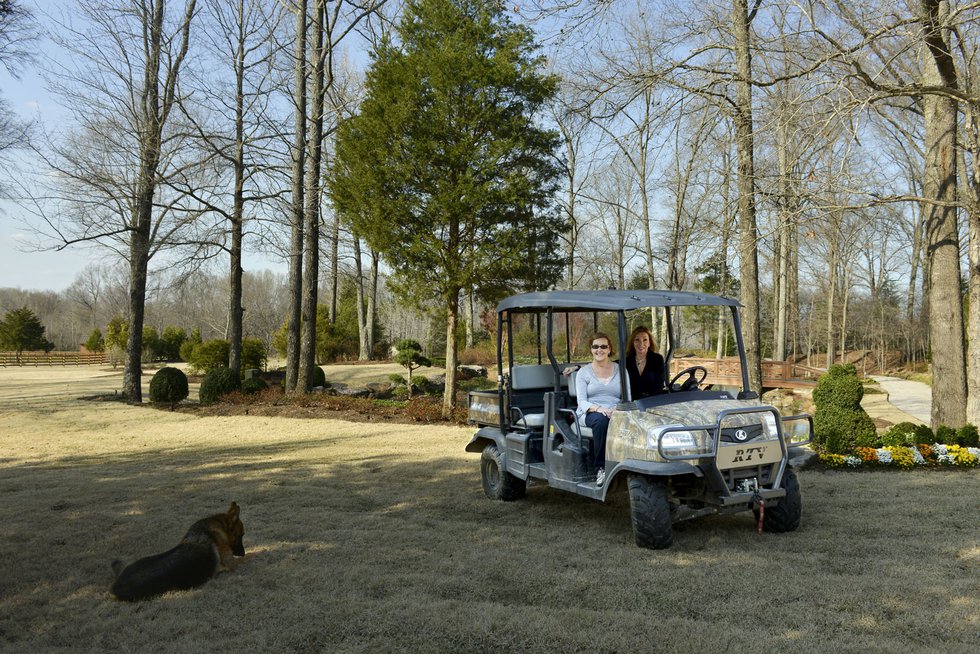 Marcia Malone (left), with her top-notch designer Ami Austin, poses on one of several all-terrain vehicles used to traverse the extensive property.