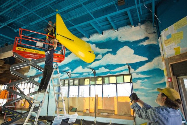 Workers install one half of a one-seater airplane, transformed as a crop duster with yellow paint, inside soon-to-open Belly Acres designed by Memphis-based Glennys Cowles Designs. 